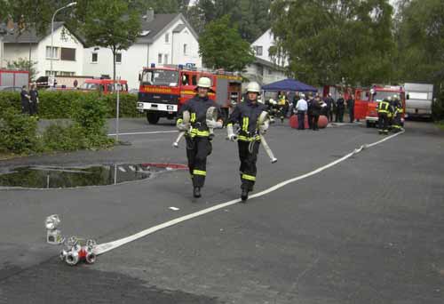 Zwei Feuerwehrmaenner laufen waehrend einer Uebung mit Schlaeuchen